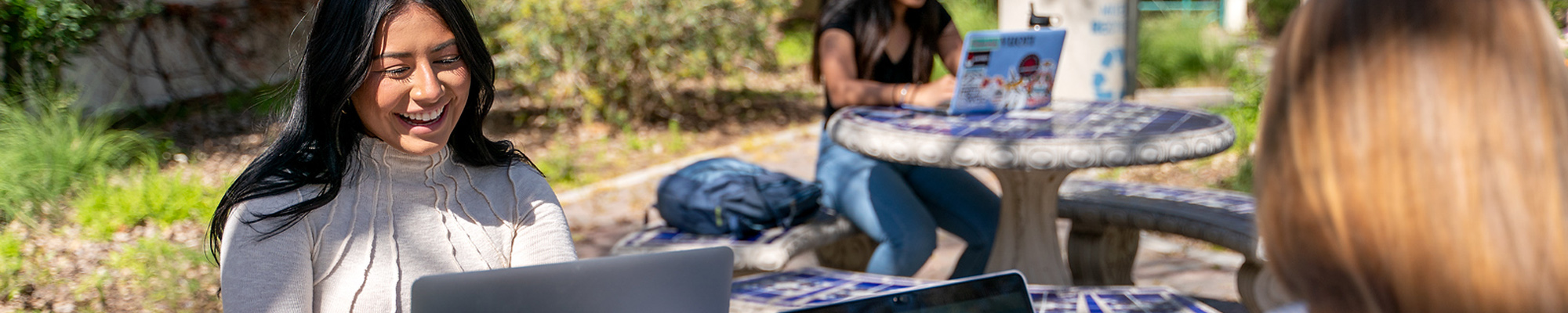 students outside working on laptops